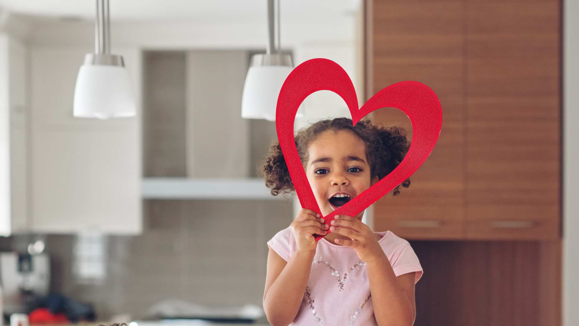 A child holding a big paper heart in a kitchen, shared for Valentine´s Day and autism