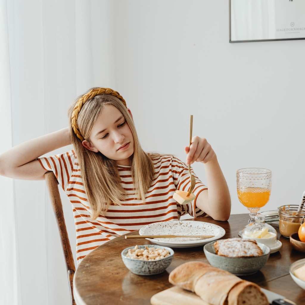 A teenage girl at the table, struggling with food textures, reflecting experiences related to a late autism diagnosis