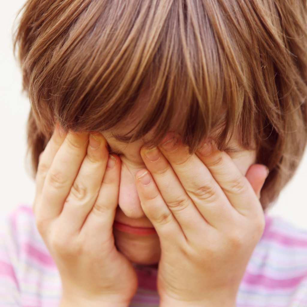 Child covering their face with both hands, showing signs of sensory overload