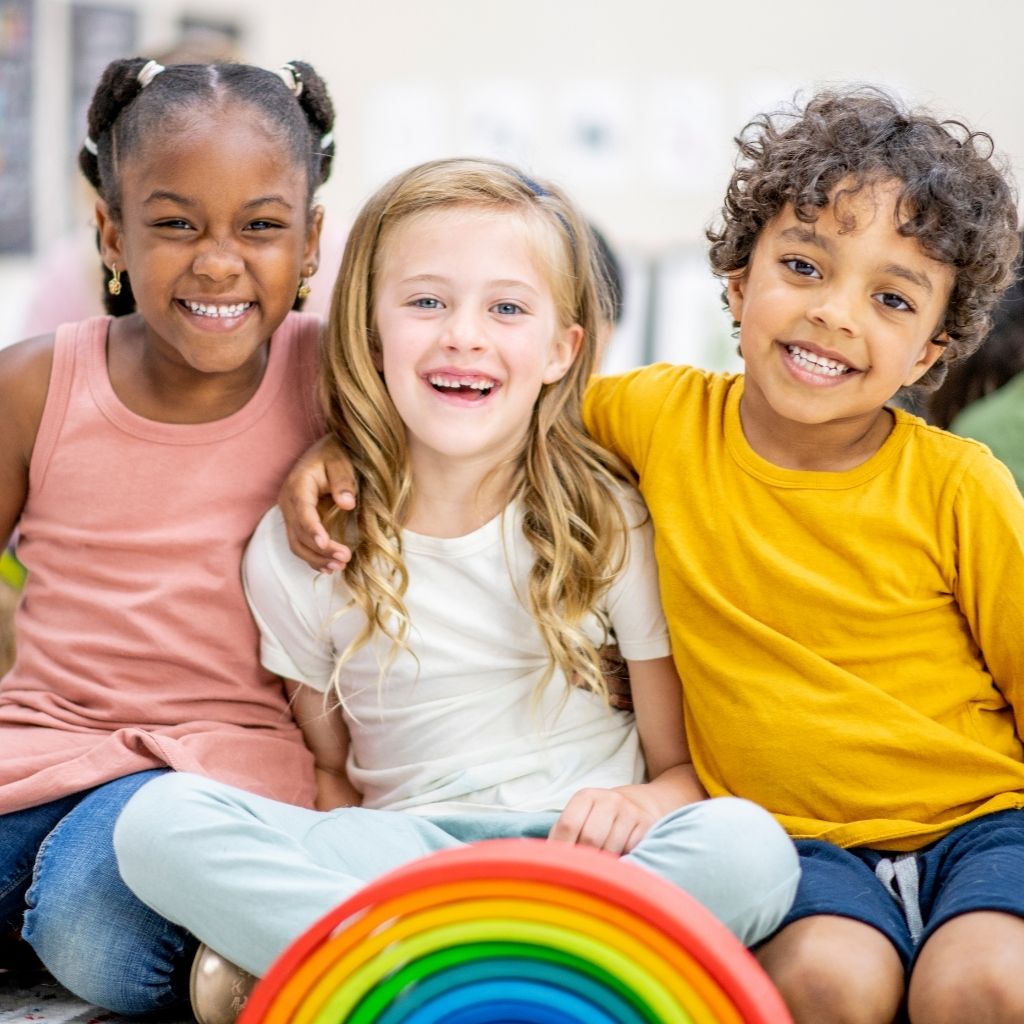 Children sitting together and smiling, helping set the scene to talk about common questions about autism.