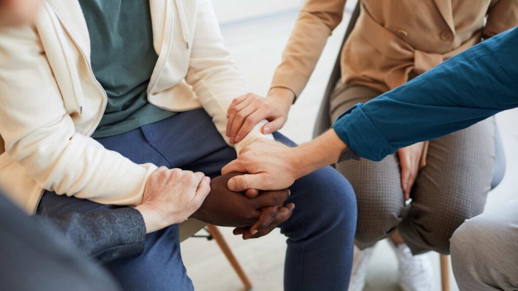 Several adults placing their hands together, showing unity and autism support.
