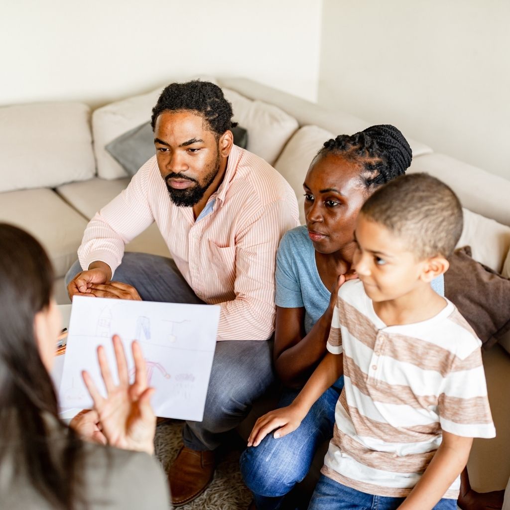 Parents and child meeting with a professional at home to talk about parent involvement in ABA therapy